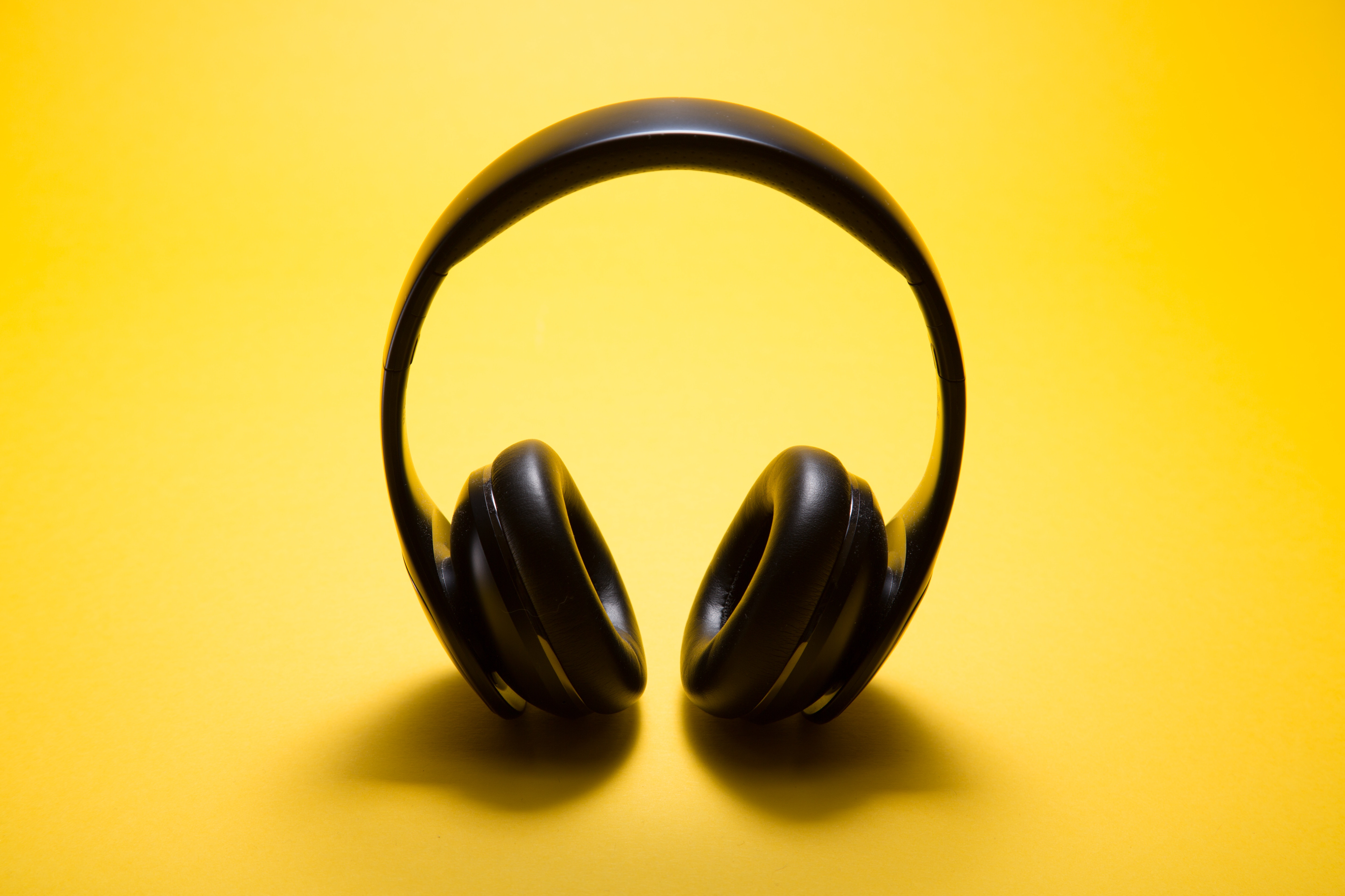 An image of black headphones with a yellow background.