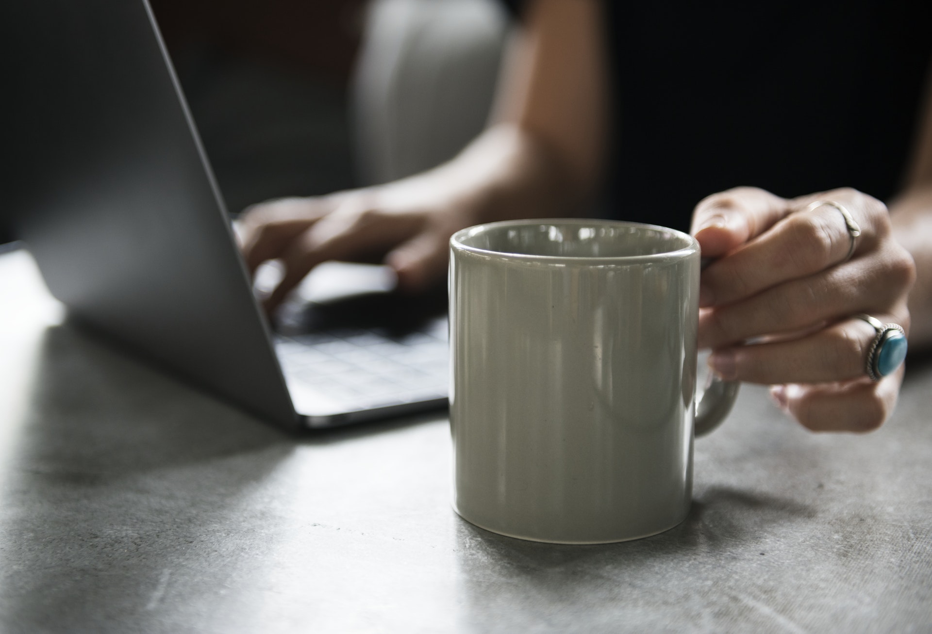 This is an image of a woman on her computer, holding a coffee mug.