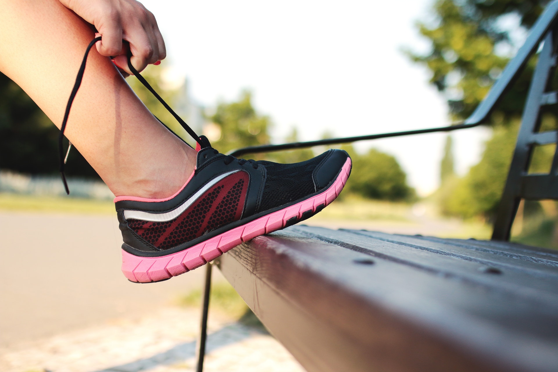 An image of a woman lacing up her running shoes on a bench.