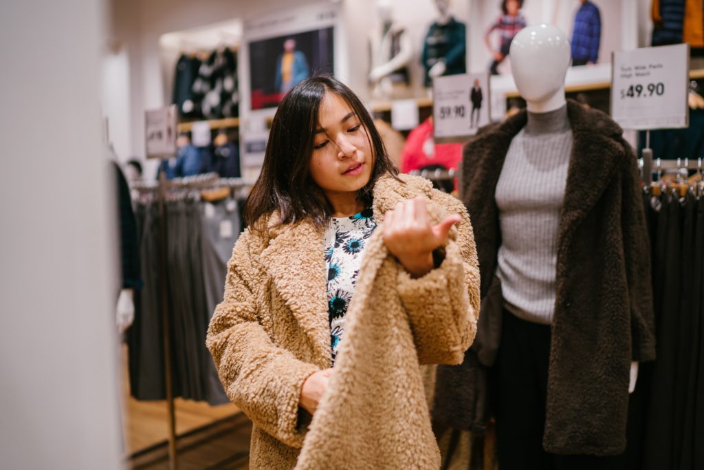 Female shopper looking at coat while wearing it.