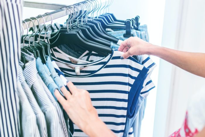 Shopper browsing through rack of shirts inside a store.