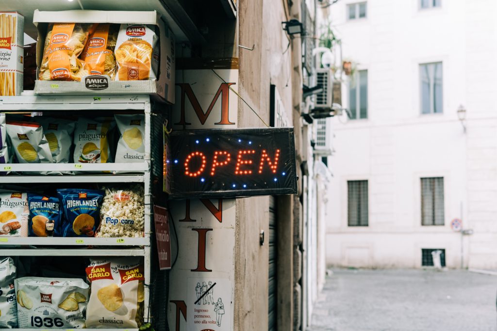 Snack food on outdoor shelf next to an Open sign